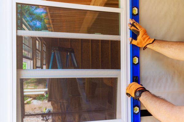 During construction of new home, construction worker installs plastic windows